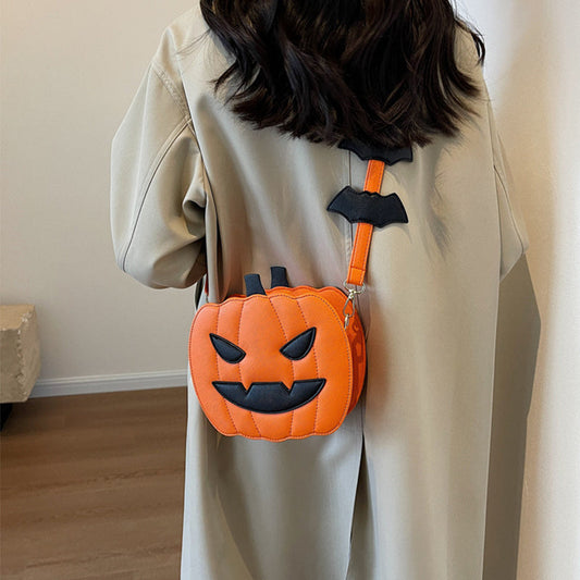 Person wearing a pumpkin-shaped bag with bat wings on a plain background
