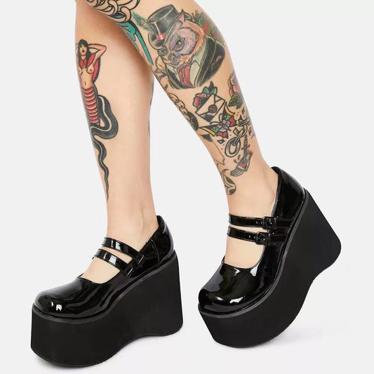 Black platform shoes worn with tattoos on a white background