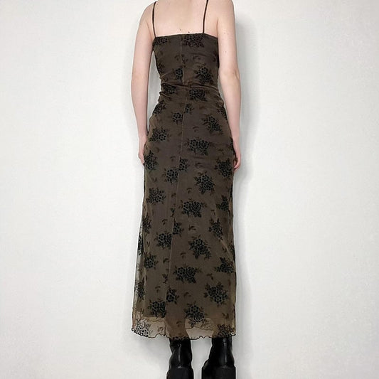 Person wearing a dark floral dress against a white background