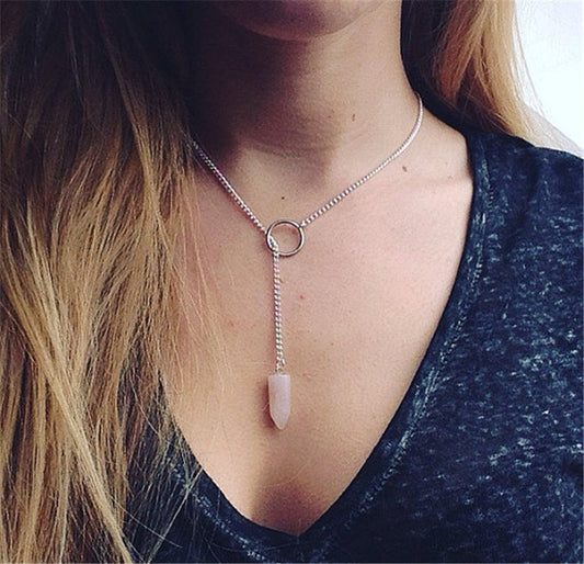 Necklace with a pink pendant worn by a person with blonde hair.