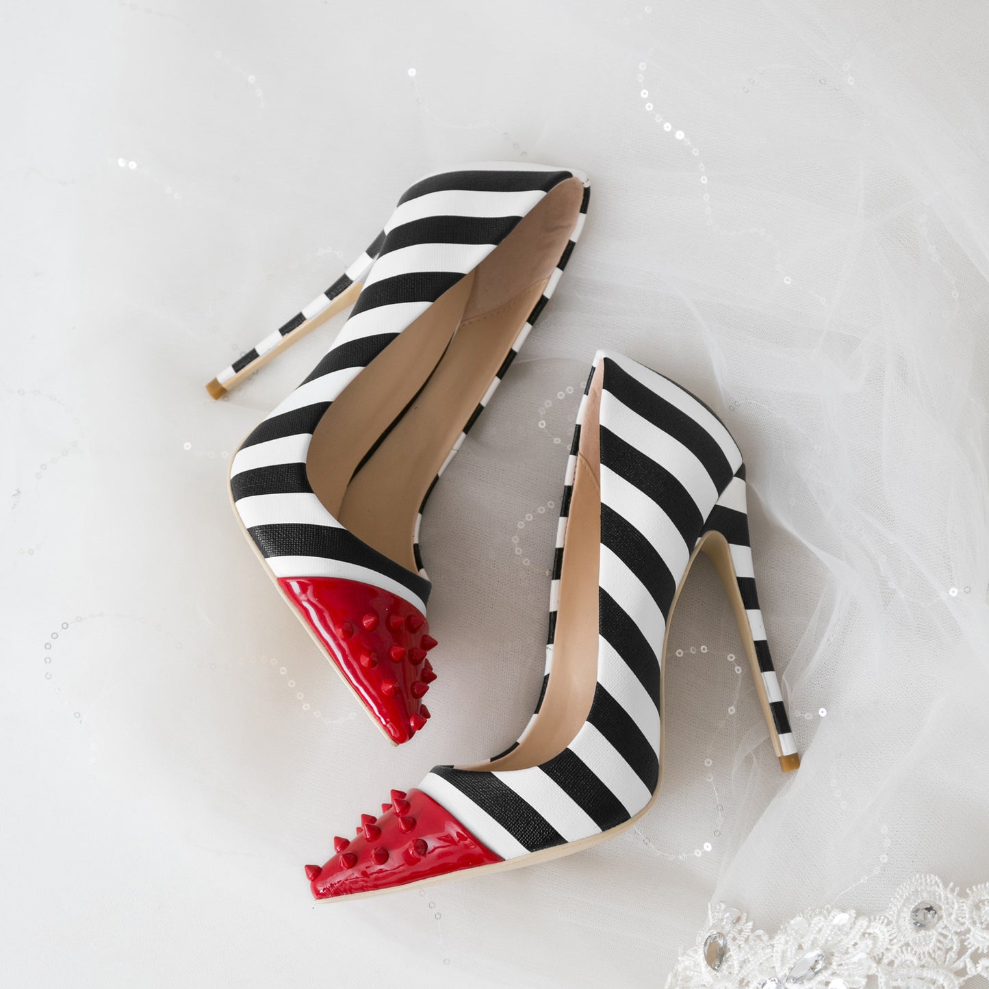 Black and white striped high heels with red soles on a white background