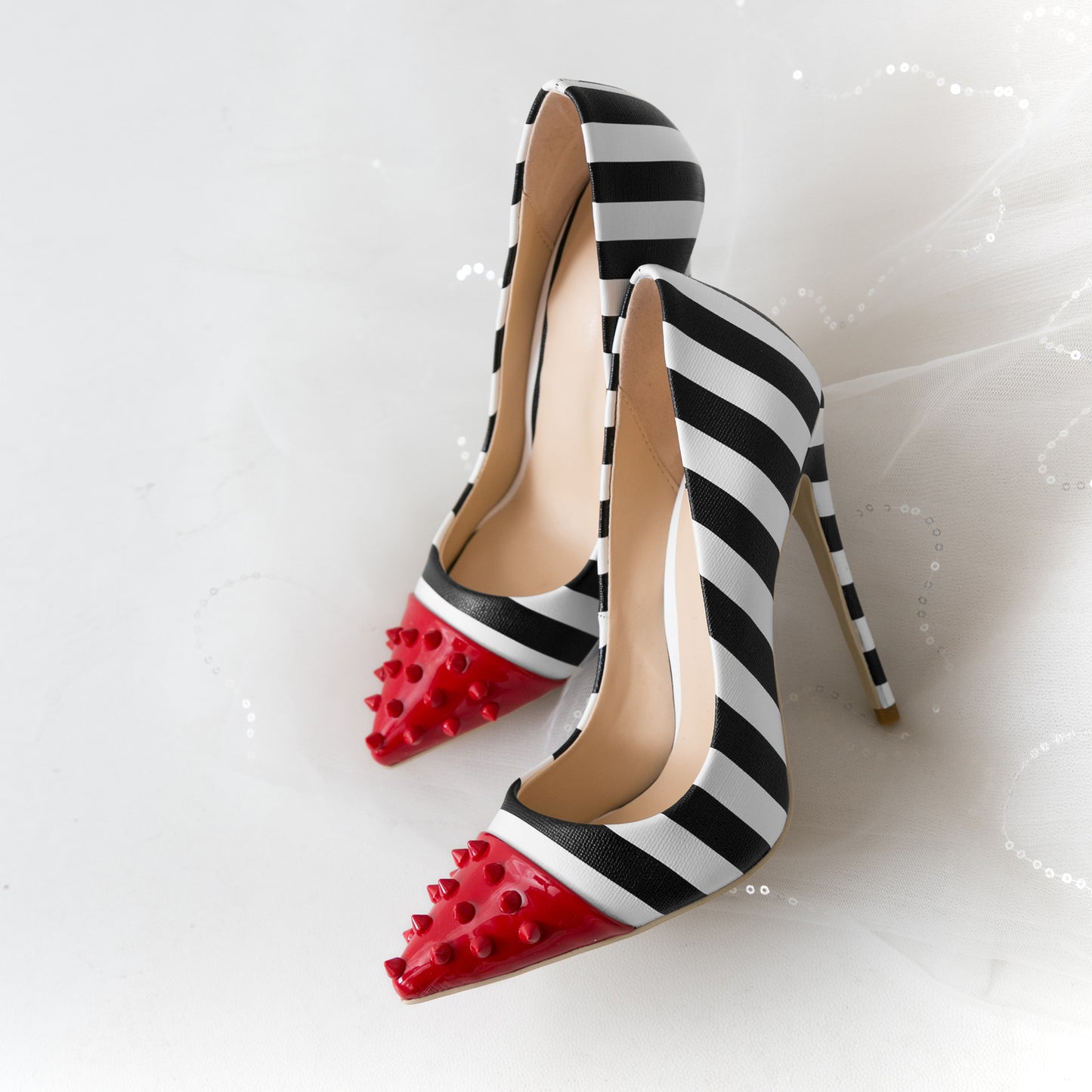 Black and white striped high heels with red spiked toes on a light gray background