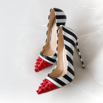 Black and white striped high heels with red spiked toes on a light gray background