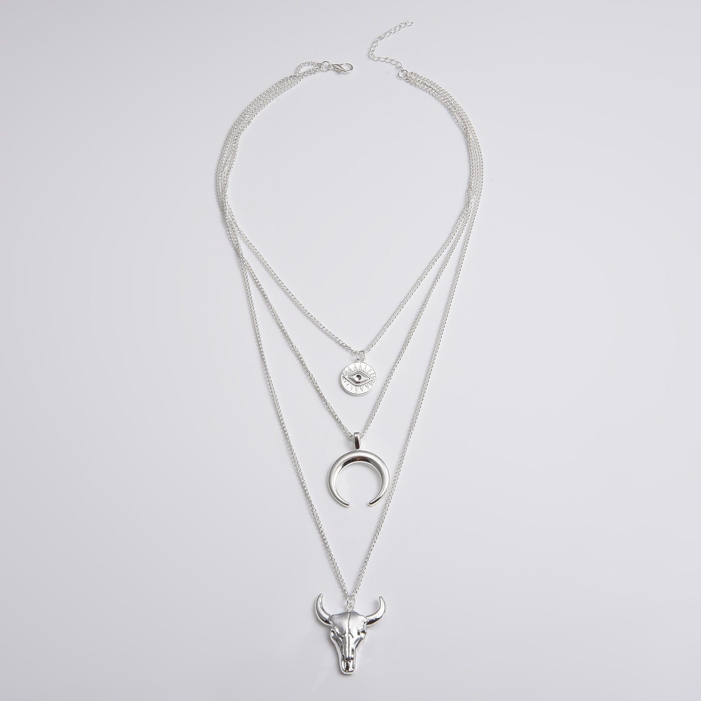 Silver layered necklace with bull head and moon pendant on a light gray background