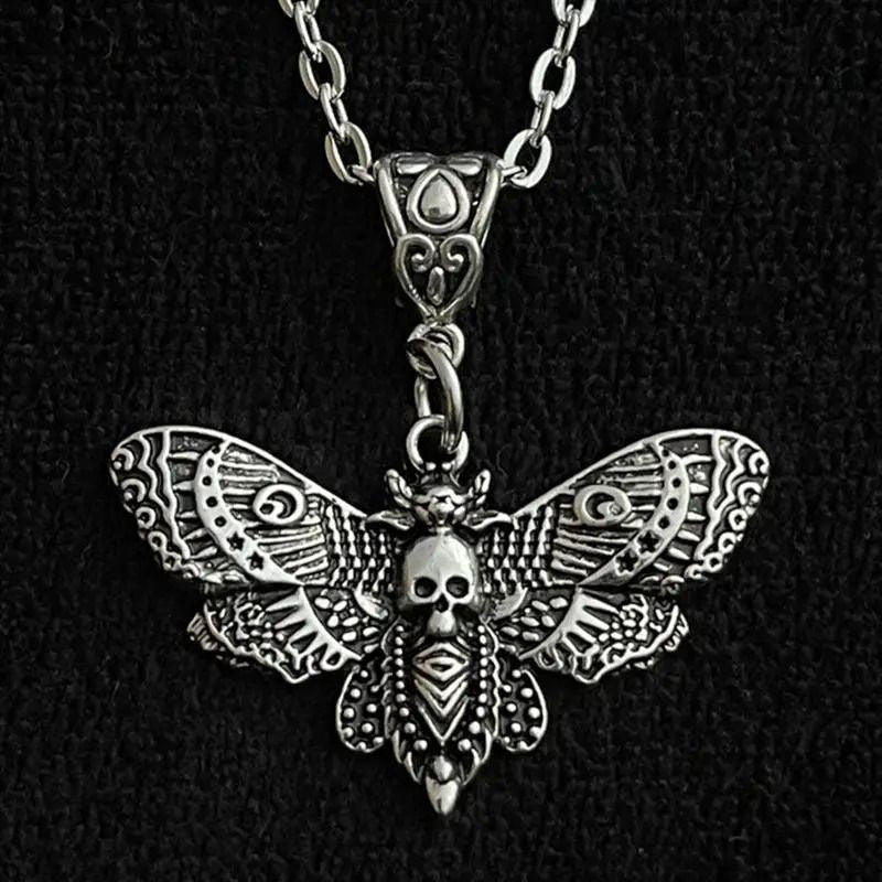 Silver moth-shaped pendant with skull design on a black background