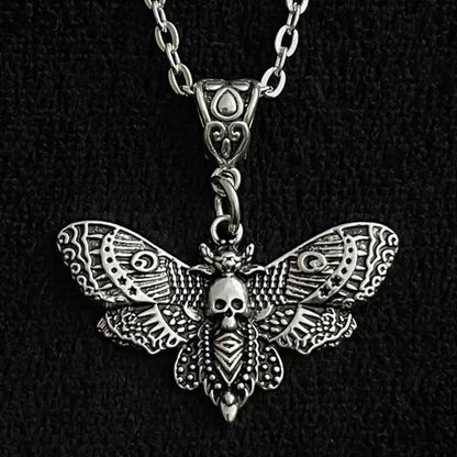Silver moth-shaped pendant with skull design on a black background