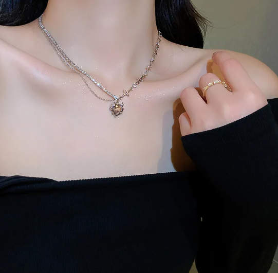 Necklace with a heart-shaped pendant worn by a person, with a blurred background.