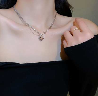 Necklace with a heart-shaped pendant worn by a person, with a blurred background.