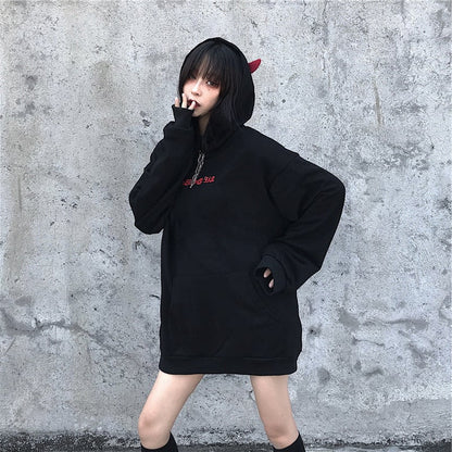 Person wearing a black hoodie with red text against a gray concrete wall