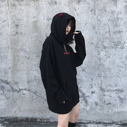 Person wearing a black hoodie with red text against a gray concrete wall
