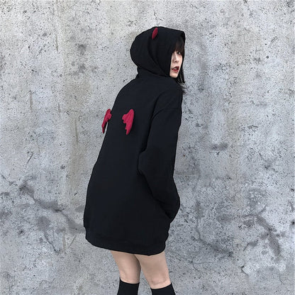 Person wearing a black hoodie with red accents against a gray concrete wall