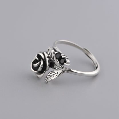 silver ring with rose detail and black stones on grey background