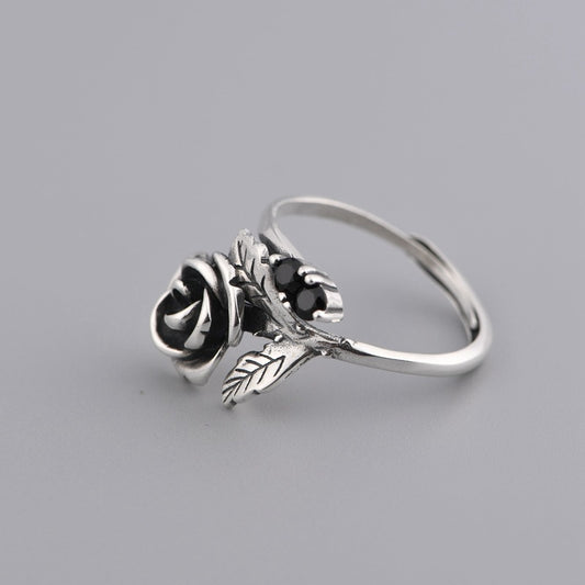 silver ring with rose detail and black stones on grey background