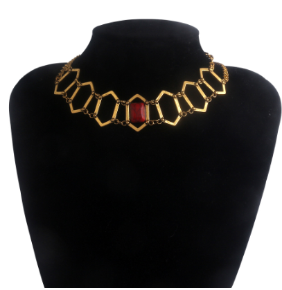 A gold-toned geometric link necklace displayed on a black velvet jewelry bust against a white background.