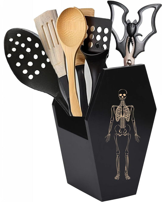 Black utensil holder with skeleton design containing kitchen utensils on a white background