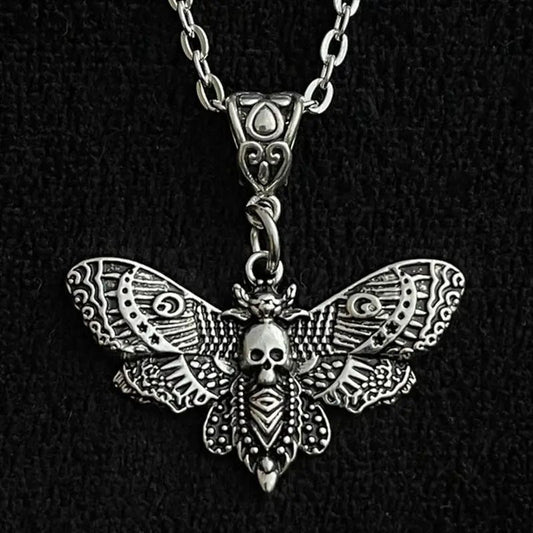 Silver moth-shaped pendant with skull design on a black background