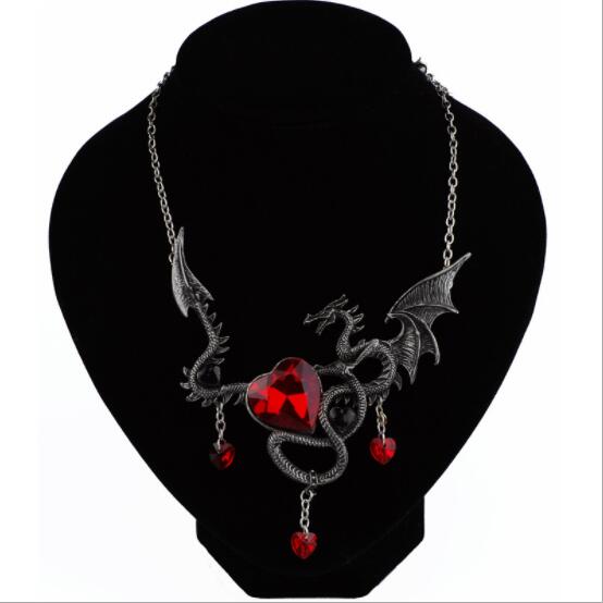 Gothic-style necklace with red heart and dragon design on a black stand.