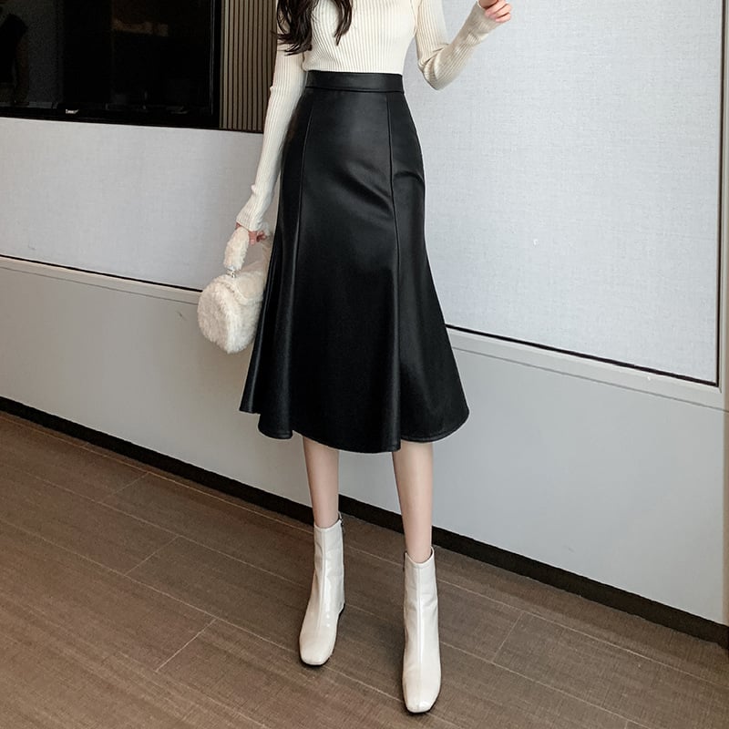 Person wearing a black leather skirt with white shoes in an indoor setting