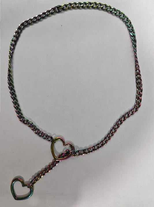 A vintage-style chain necklace with a heart-shaped clasp and a dangling heart pendant, featuring a dark metallic finish with subtle iridescent green and gold reflections, displayed on a plain light gray background.