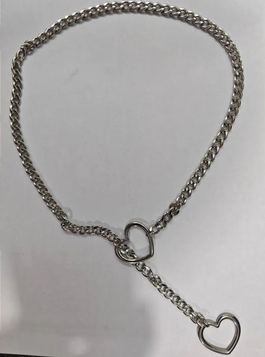 A silver metal chain accessory with a heart-shaped ring clasp and a heart-shaped ring on the end, displayed on a plain light gray background.