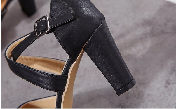 Black high-heeled shoe with a strap and buckle on a gray background