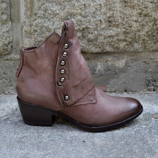 Brown leather boot with studded details on a stone surface