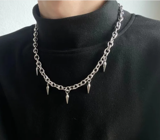 Silver chain necklace with spikes worn by a person in a black turtleneck.