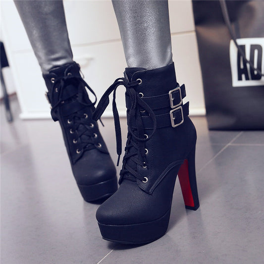 Black high-heeled platform boots with red soles worn by a person.