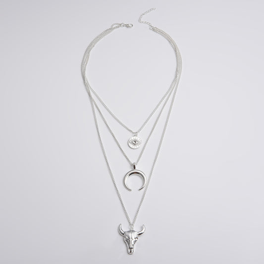 Silver layered necklace with bull head and moon pendant on a light gray background