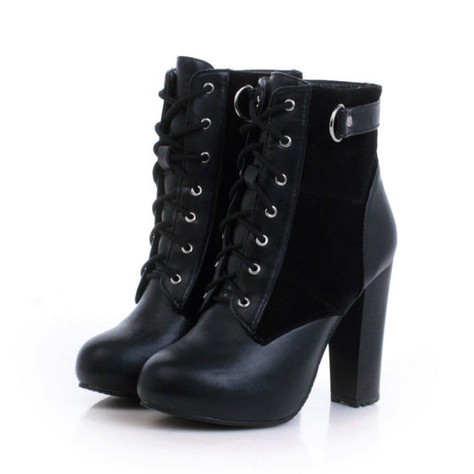 A pair of black lace-up ankle boots with a chunky block heel, featuring a mix of smooth and suede-like textures, silver-tone eyelets, and a decorative strap with a ring on the side.