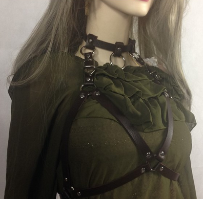 Mannequin wearing a green top with a black harness on a plain background