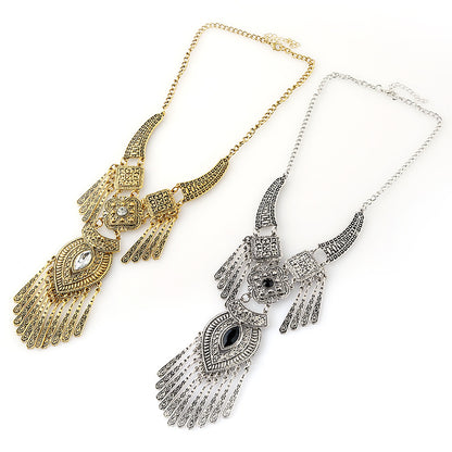 Two ornate statement necklaces with detailed filigree and fringe designs, one in gold-tone metal and one in silver-tone metal, displayed on a clean white background.