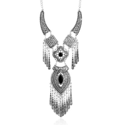 A silver-toned statement necklace with intricate filigree patterns, dangling chains, and black inlay details, shown against a plain white background.