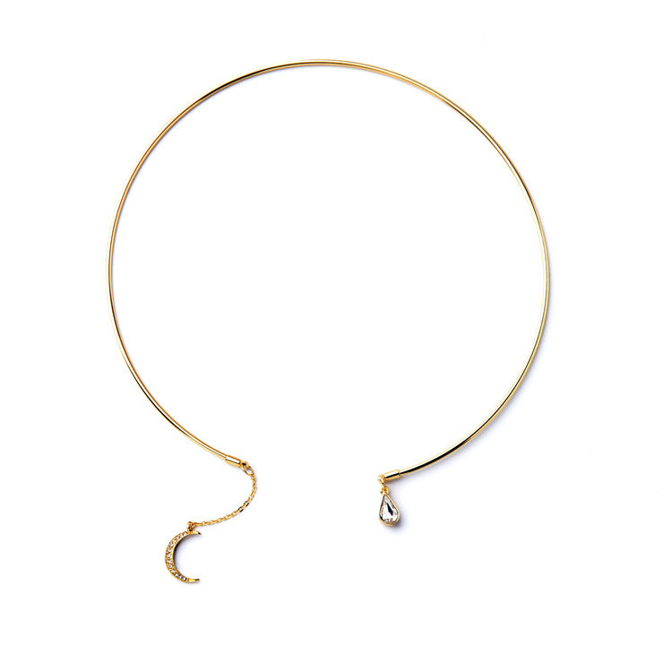 A delicate gold-toned choker necklace with a small crescent moon charm set with tiny clear stones and a teardrop-shaped clear stone pendant, displayed on a clean white background.