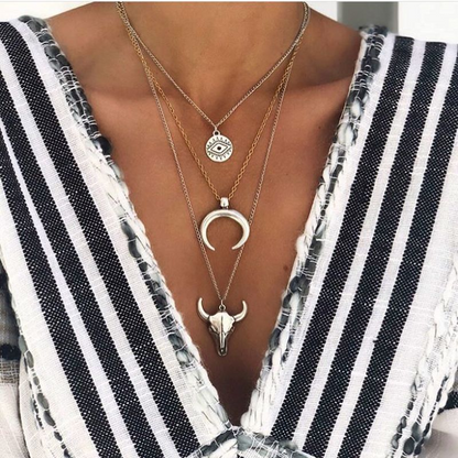 Layered necklaces with pendants on a person wearing a black and white striped top.