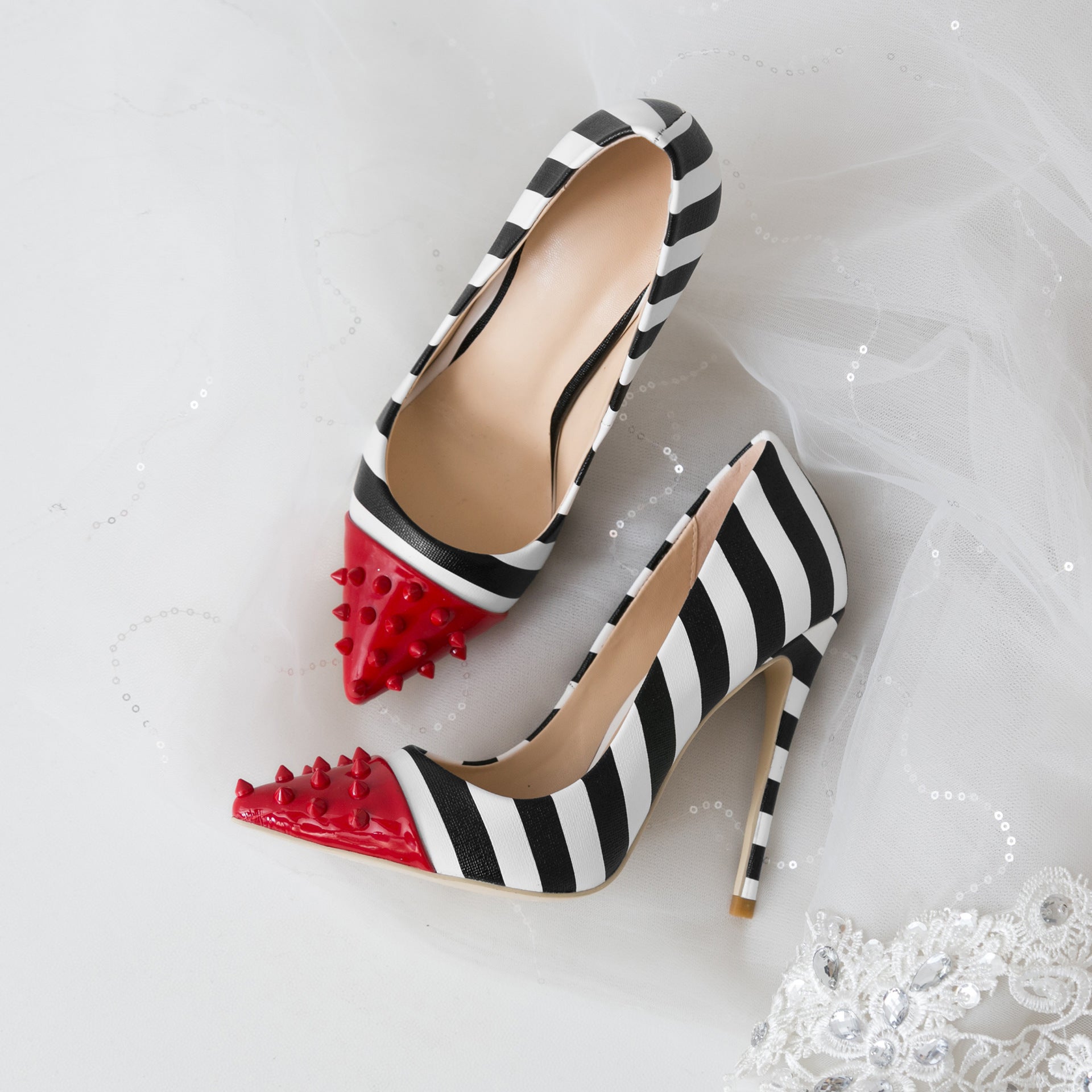 Black and white striped high heels with red spiked toes on a white background