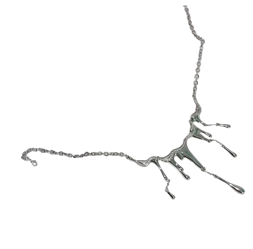 A silver-toned necklace with a dripping, tree-like pendant design, displayed on a white ceramic plate against a white textured fabric background.
