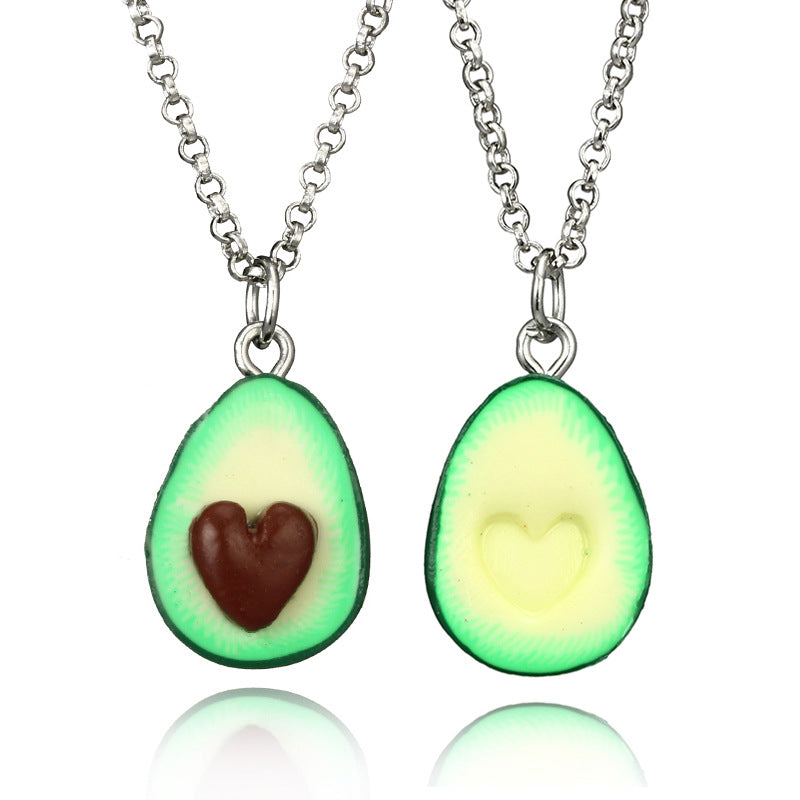 Two avocado-shaped pendants on silver chains against a white background